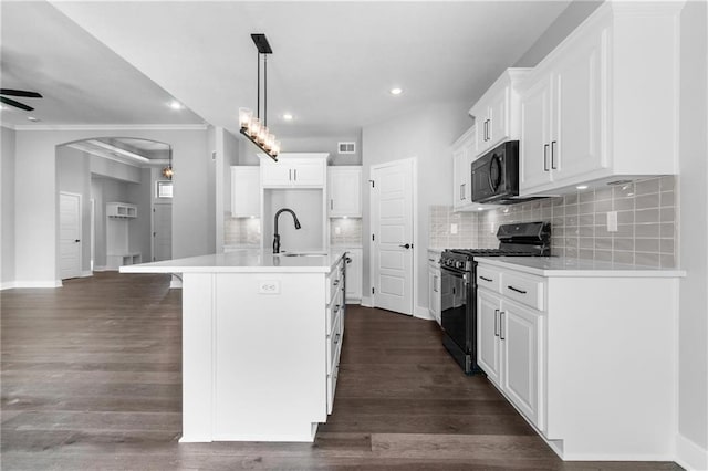 kitchen with arched walkways, gas stove, ceiling fan, a sink, and black microwave