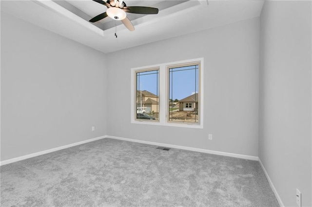 empty room with ceiling fan, carpet, a raised ceiling, and baseboards