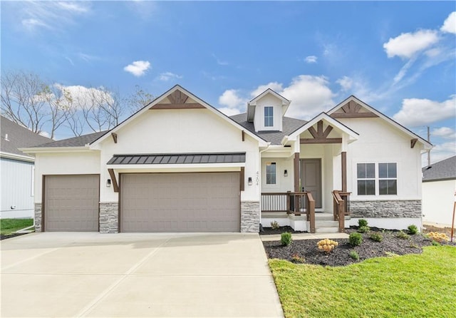 view of front of home featuring concrete driveway, stone siding, an attached garage, a standing seam roof, and stucco siding