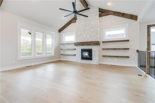 unfurnished living room with a stone fireplace, wood finished floors, beam ceiling, and baseboards