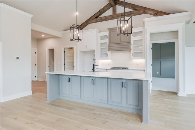 kitchen with light countertops, backsplash, a sink, and light wood-style floors