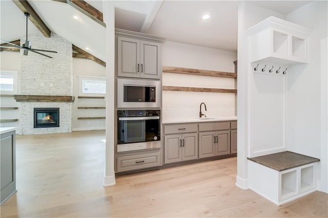 kitchen with open shelves, appliances with stainless steel finishes, a sink, and gray cabinetry