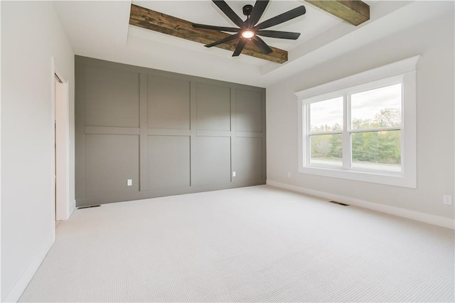 unfurnished bedroom featuring light carpet, baseboards, visible vents, a raised ceiling, and beamed ceiling