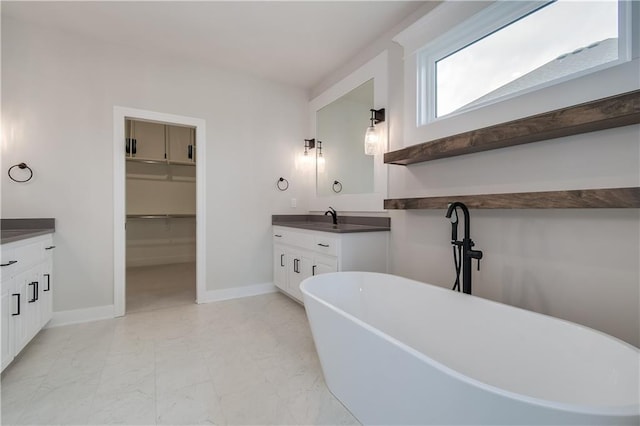 bathroom featuring a freestanding tub, vanity, baseboards, and marble finish floor