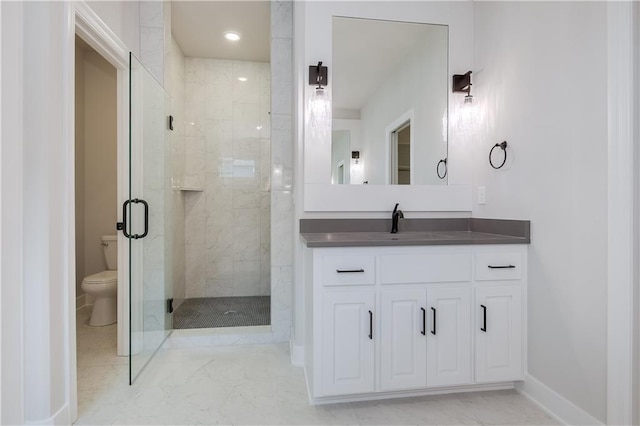 bathroom featuring baseboards, toilet, a shower stall, and vanity