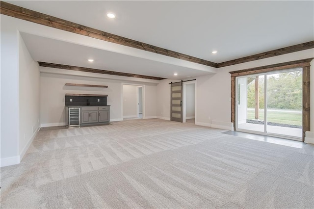 unfurnished living room with recessed lighting, light colored carpet, baseboards, and a barn door