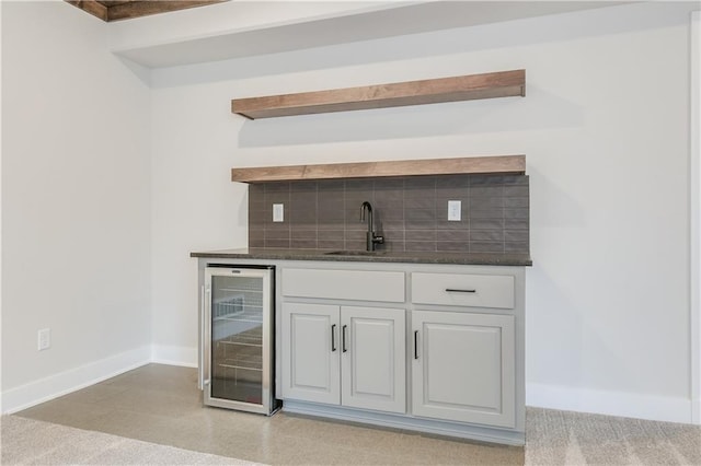 bar featuring beverage cooler, a sink, backsplash, and baseboards