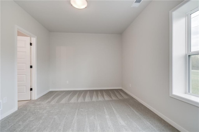 spare room featuring carpet, visible vents, and baseboards