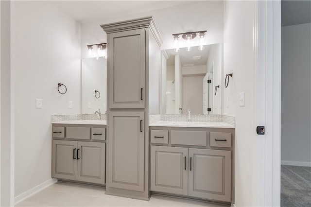 full bath featuring two vanities, a sink, and baseboards