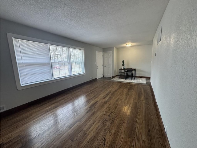 10904 Cambridge Ave, Kansas City, MO 64134 - interior space featuring dark wood-style floors, a textured wall, a textured ceiling, and baseboards
