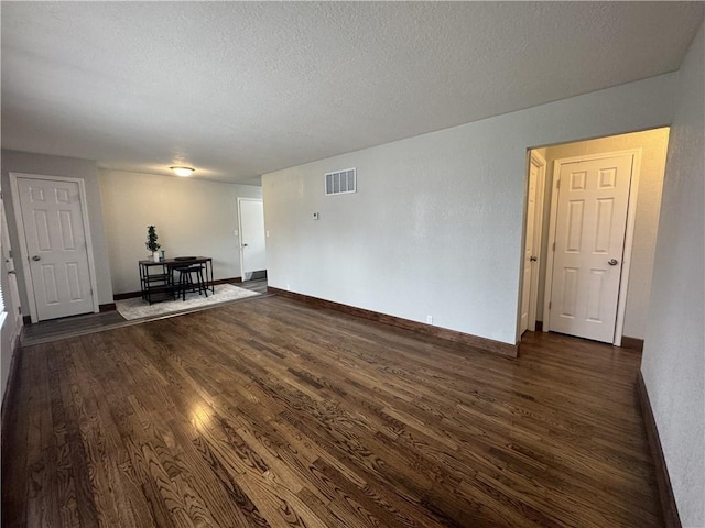 10904 Cambridge Ave, Kansas City, MO 64134 - unfurnished living room featuring visible vents, dark wood finished floors, a textured ceiling, and baseboards