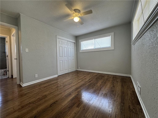 10904 Cambridge Ave, Kansas City, MO 64134 - unfurnished bedroom featuring a closet, a textured wall, dark wood-type flooring, a textured ceiling, and baseboards