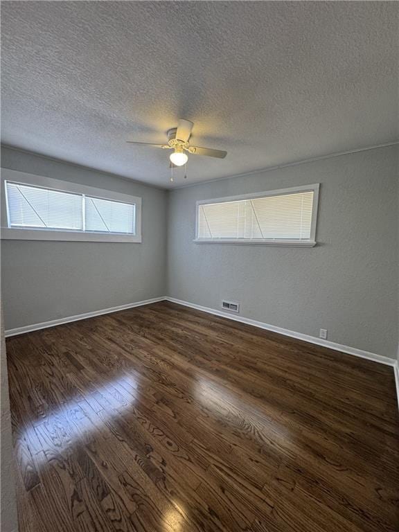 10904 Cambridge Ave, Kansas City, MO 64134 - spare room with ceiling fan, a textured ceiling, dark wood-type flooring, visible vents, and baseboards