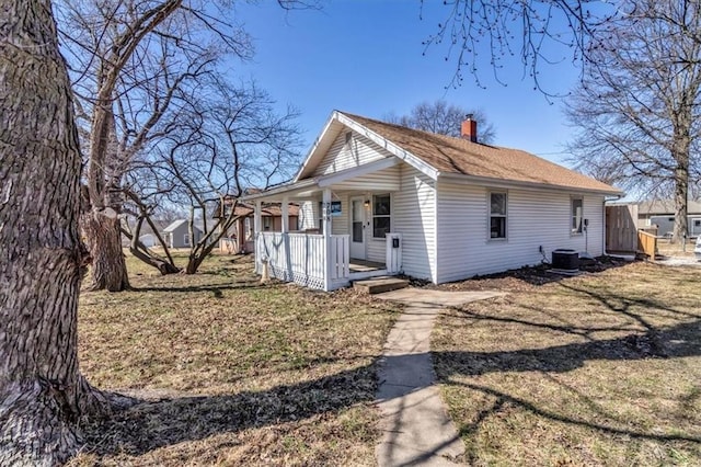 view of home's exterior with a yard, covered porch, central AC, and a chimney