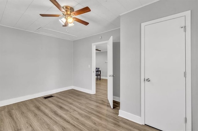 spare room featuring visible vents, ceiling fan, baseboards, attic access, and wood finished floors