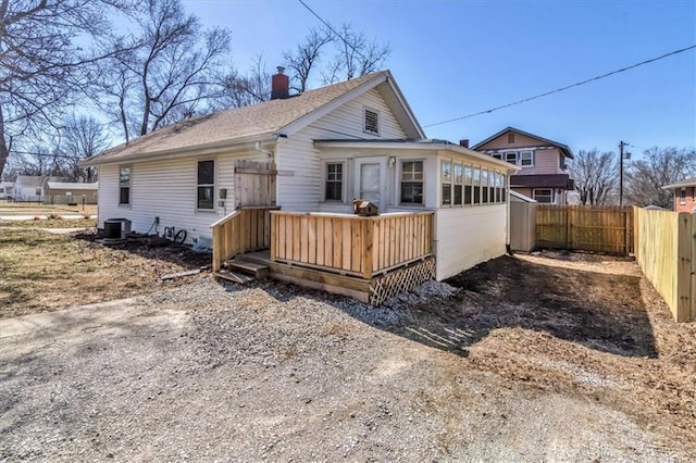 back of house with central air condition unit, fence, a chimney, and a wooden deck