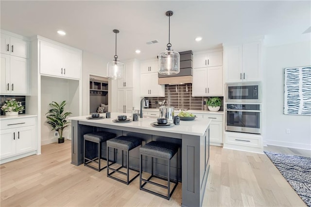 12435 NW Arbor Way, Platte City, MO 64079 - kitchen with stainless steel oven, built in microwave, backsplash, wall chimney range hood, and light wood-type flooring