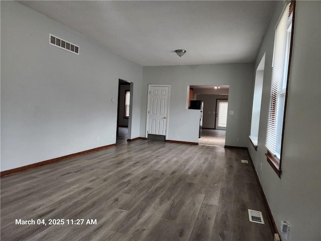 unfurnished living room featuring visible vents, dark wood finished floors, and baseboards