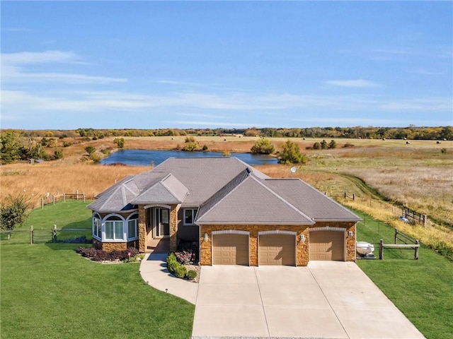 view of front of house with concrete driveway, a water view, an attached garage, fence, and a front lawn