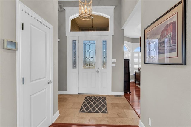 foyer entrance with a notable chandelier and baseboards