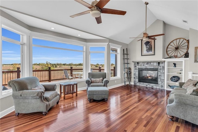 living room with lofted ceiling, a stone fireplace, wood finished floors, visible vents, and baseboards