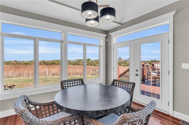 dining room featuring baseboards, wood finished floors, visible vents, and an inviting chandelier