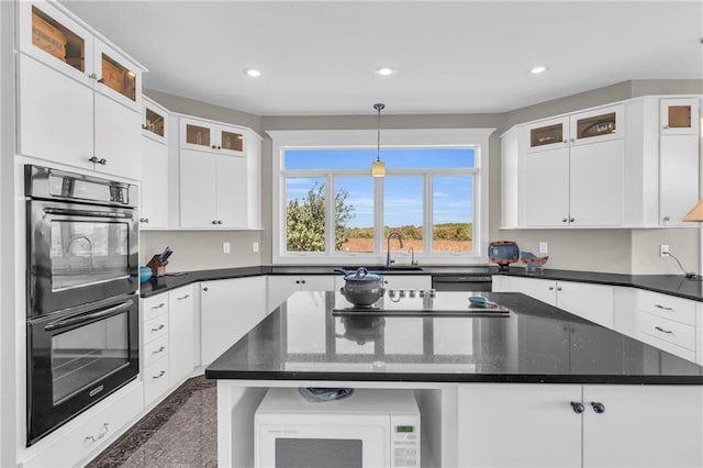 kitchen featuring recessed lighting, a sink, white cabinetry, a center island, and black appliances