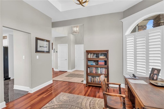 home office with a chandelier, baseboards, and wood finished floors