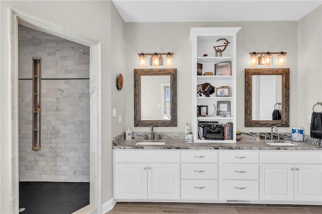 full bathroom featuring a sink, a tile shower, and double vanity