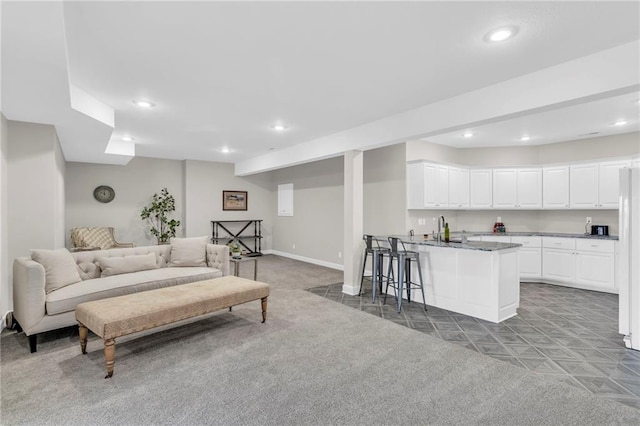 carpeted living area featuring baseboards, a sink, and recessed lighting