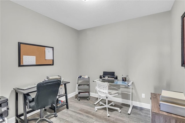 office space featuring a textured ceiling, wood finished floors, and baseboards