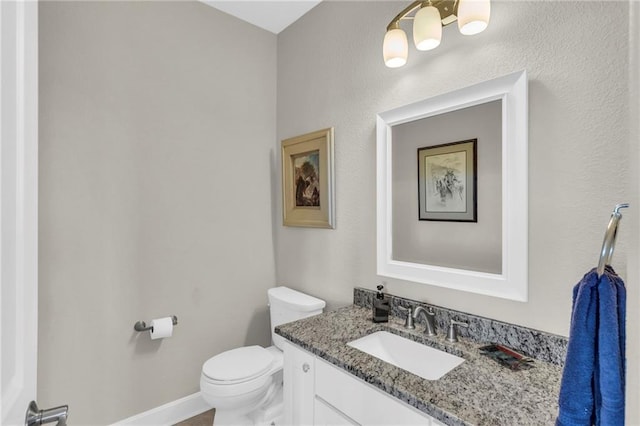 half bathroom featuring toilet, baseboards, and vanity