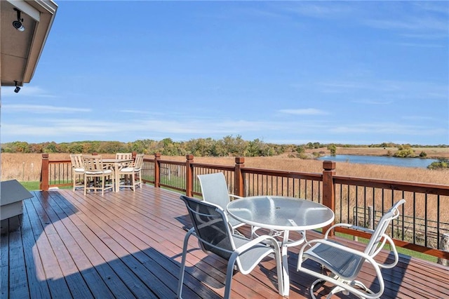 wooden terrace featuring a water view and outdoor dining space