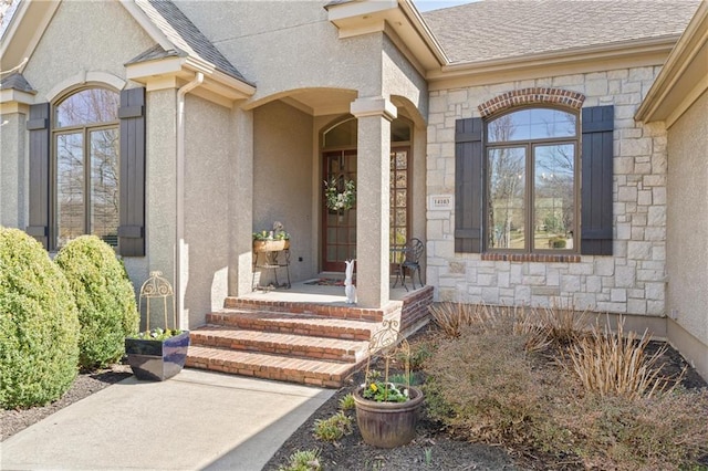 property entrance with stucco siding, stone siding, and a shingled roof