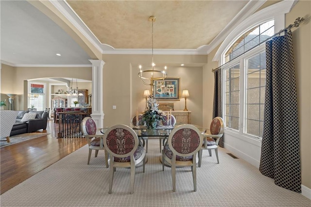 dining area with an inviting chandelier, decorative columns, crown molding, and visible vents