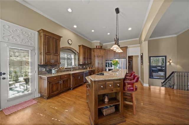 kitchen featuring a center island, light stone counters, decorative backsplash, light wood-style floors, and stainless steel appliances