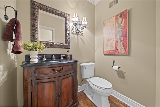 bathroom with visible vents, toilet, wood finished floors, baseboards, and vanity