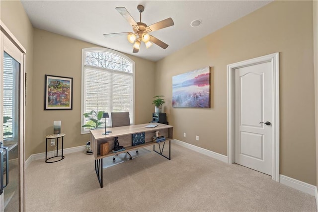 carpeted office space with a ceiling fan and baseboards