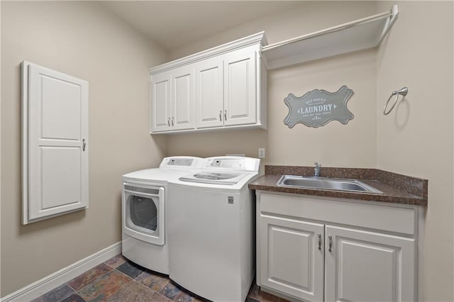 laundry room featuring a sink, stone finish flooring, cabinet space, baseboards, and washing machine and clothes dryer