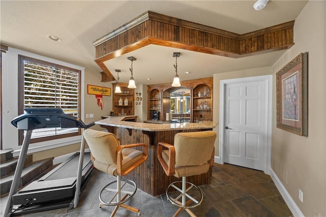 bar featuring hanging light fixtures, a textured ceiling, wet bar, and baseboards