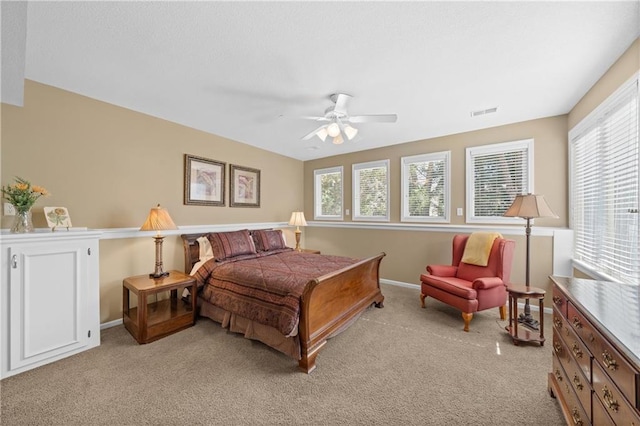 bedroom featuring visible vents, baseboards, light colored carpet, and a ceiling fan