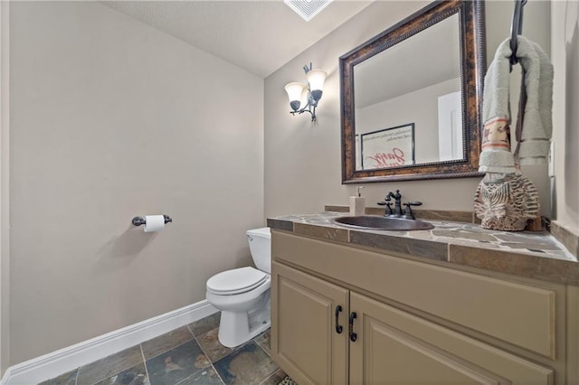 half bath featuring visible vents, toilet, stone finish flooring, baseboards, and vanity