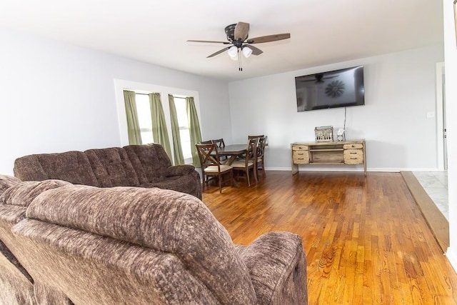 living area with a ceiling fan, baseboards, and wood finished floors