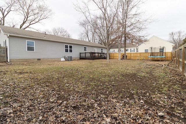 rear view of property with crawl space, a trampoline, a fenced backyard, and central air condition unit