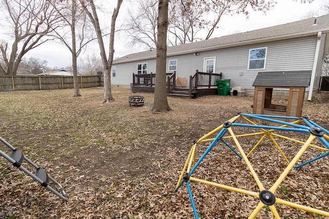 exterior space featuring a fire pit, a playground, fence, and a deck