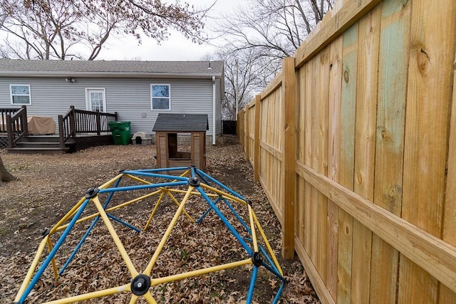 view of yard featuring a playground, a fenced backyard, and a wooden deck