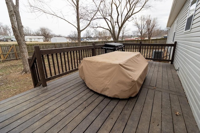 wooden terrace with a fenced backyard and a grill