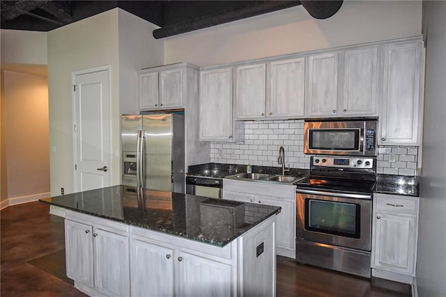 kitchen featuring tasteful backsplash, white cabinets, appliances with stainless steel finishes, a center island, and a sink