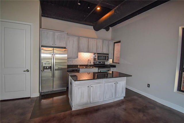 kitchen with stainless steel appliances, a kitchen island, baseboards, tasteful backsplash, and beamed ceiling