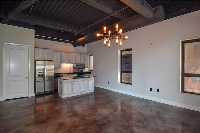 kitchen featuring concrete flooring, a sink, baseboards, appliances with stainless steel finishes, and dark countertops